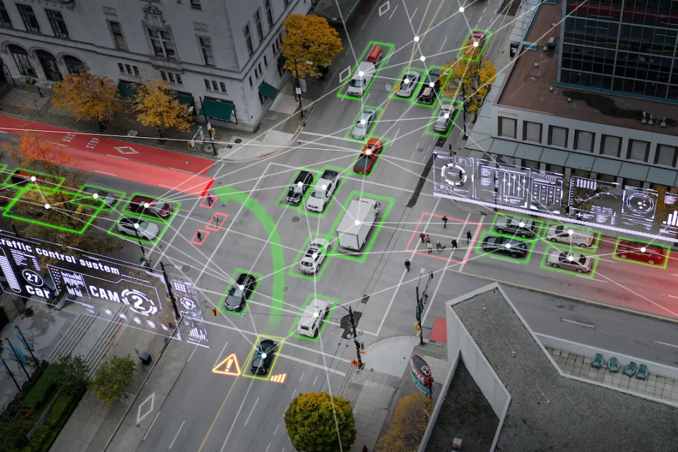 Aerial view of vehicles on city street with superimposed graphic arrows indicating autonomous cars.